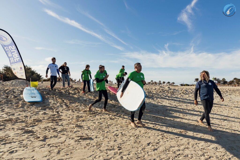 Fuertetribu Clase Surf Principiante 8 1024x683 Un grupo de principiantes del surf entra al agua con sus tablas.