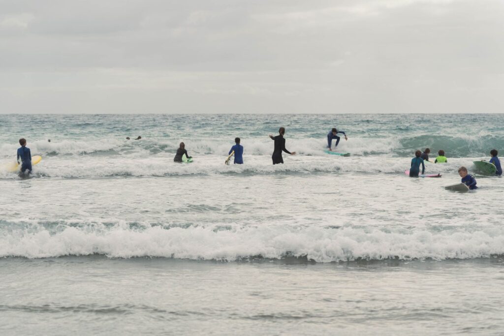 Fuertetribu Surf Para Ninos 34 1024x683 Niños intentando de surfear durante una clase de surf en grupo de niños en Fuerteventura.