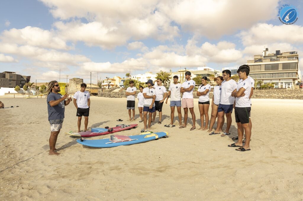 Fuertetribu Voluntariado 11 1024x682 Un instructor de surf explica a un grupo de voluntarios los fundamentos del surf adaptado en una playa de Fuerteventura.