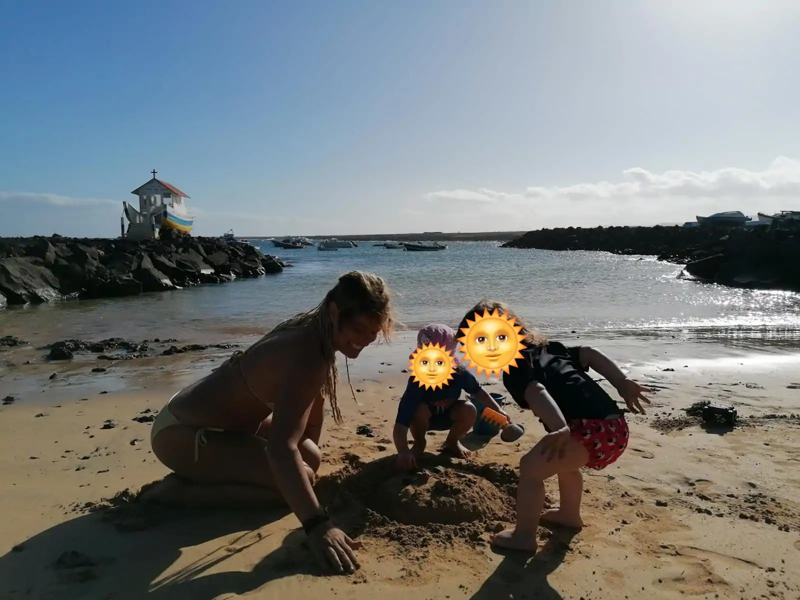La ni&ntilde;era Sonja jugando con dos ni&ntilde;os en la arena al mar.