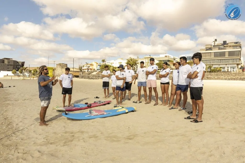 Fuertetribu Voluntariado 11 1024x682 Un instructor de surf explica a un grupo de voluntarios los fundamentos del surf adaptado en una playa de Fuerteventura.